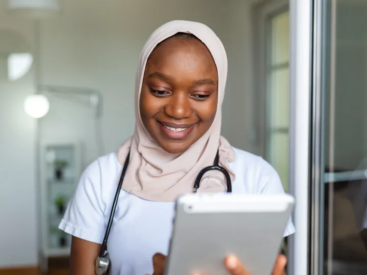 Soignante en stéthoscope souriant devant une tablette