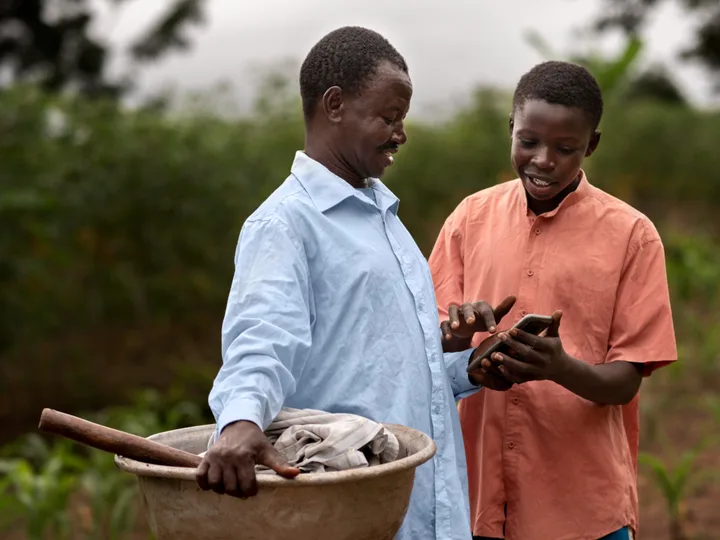 Agriculteur et un jeune garçon regardant un téléphone dans un champ de maïs