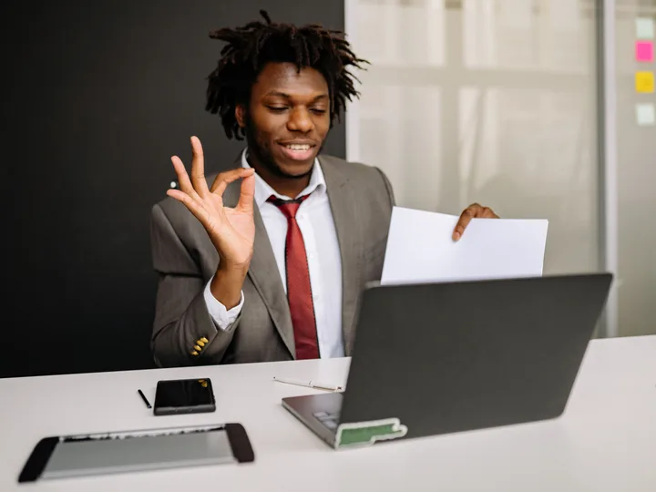 Jeune professionnel en costume devant son ordinateur portable, une feuille à la main